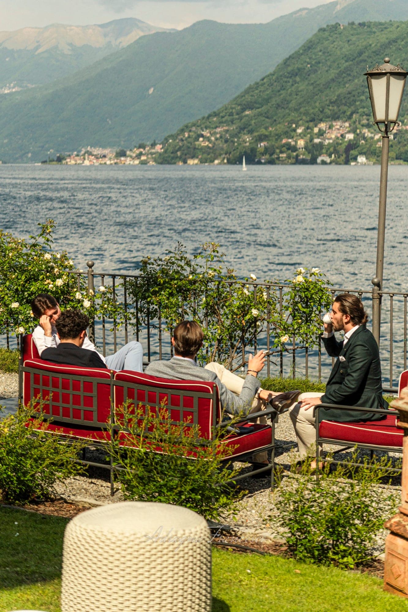 Guests relaxing on a villa terrace above Lake Como, with mountains beyond the water